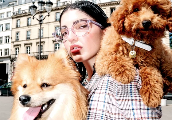 Peter and May Brillen - Frau mit Brille hält zwei braune Hunde auf dem Arm