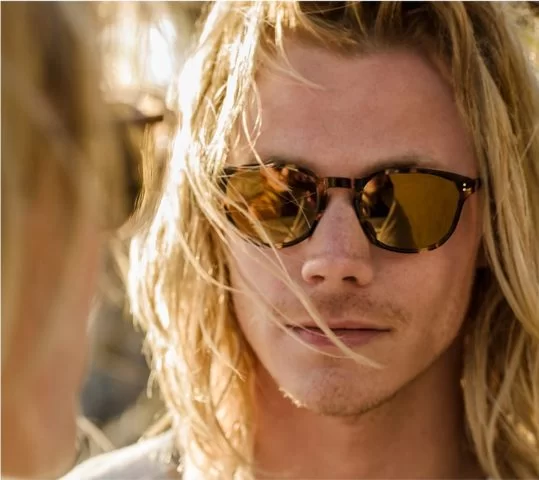 Brillenmarke - Oliver Peoples - Mann mit langen blonden Haaren und Sonnenbrille