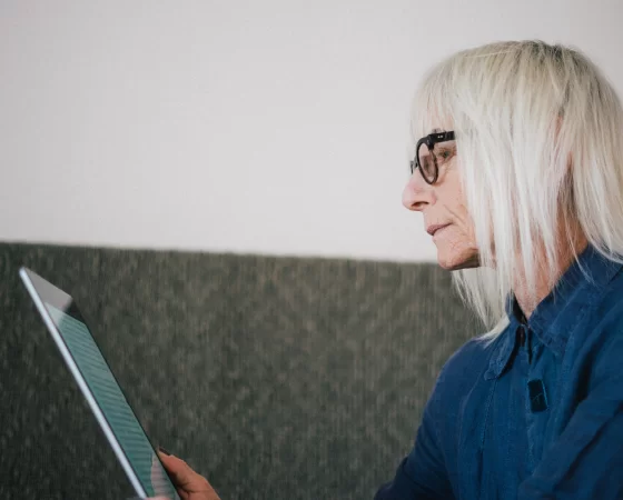 Lesebrillen - Ältere Frau mit weißem Haar liest auf Tablet mit Lesebrille auf der Nase