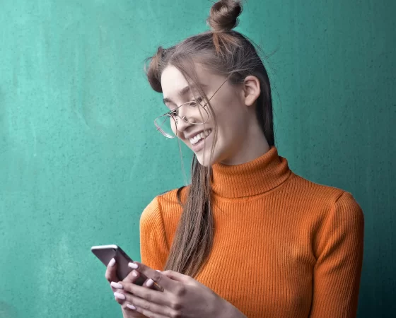 Relaxbrille - Fernbrille mit nahunterstützenden Active-Gläsern, Frau mit Smartphone in orangem Pulli